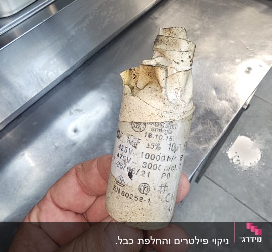 יד מחזיקה רכיב חשמלי עם כיתוב טכני